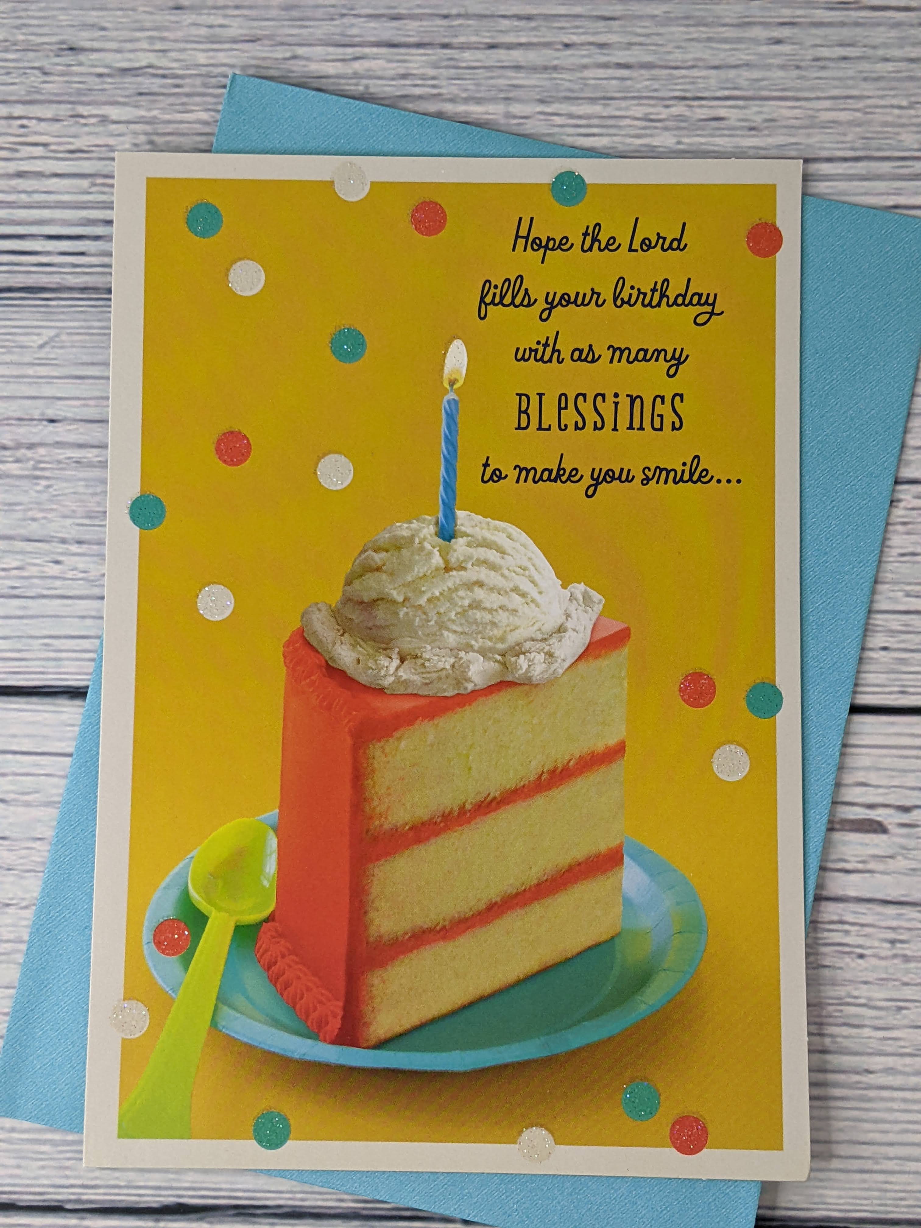 A Christian birthday card with a yellow cover that features an image of a slice of cake, topped with ice cream and a candle.